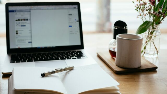 Laptop on desk with notepad