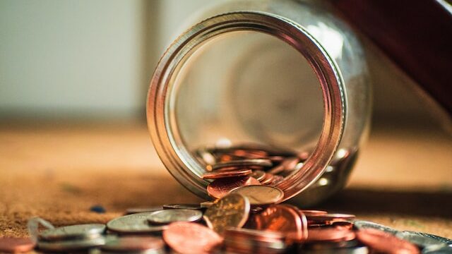 a glass jar with coins falling out of it